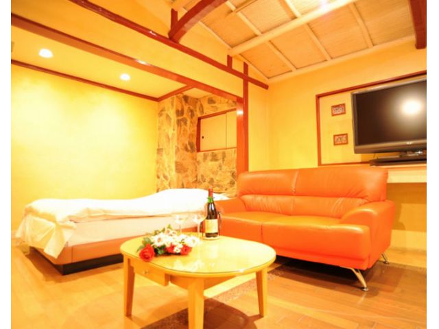 HOTEL Rupo 錦糸町の客室。明るく温かみのある空間とオレンジソファが特徴で、寝取りの伝道師クロエおすすめのグループ利用向けラブホテル。
