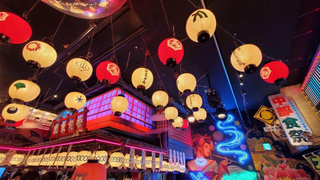 寝取りの伝道師クロエがNTR後に訪れた新宿・歌舞伎横丁の幻想的な内装。年の差カップルと祝杯を交わしたリアル寝取らせ体験のラストシーンを飾るネオンと提灯の艶やかな空間。

