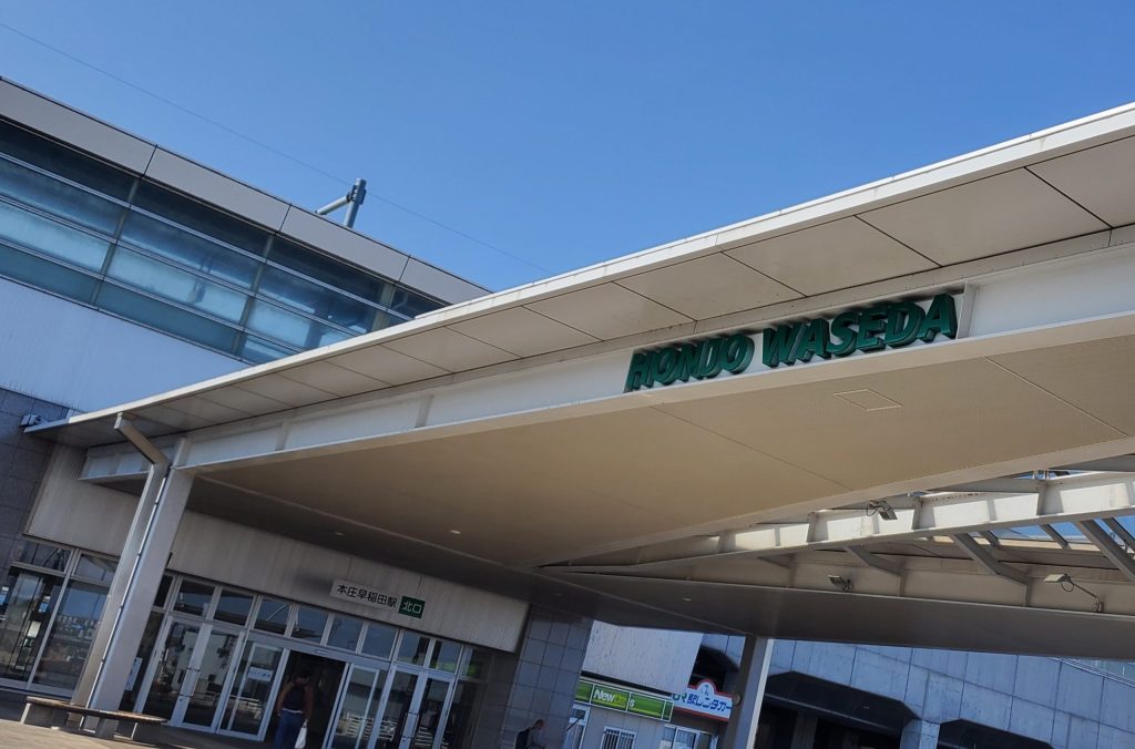 埼玉県本庄市の本庄早稲田駅北口外観。青空の下に駅名サインが見える駅前風景で、NTR体験談「ねとりっぷ埼玉編」の舞台となる本庄早稲田の現地写真。